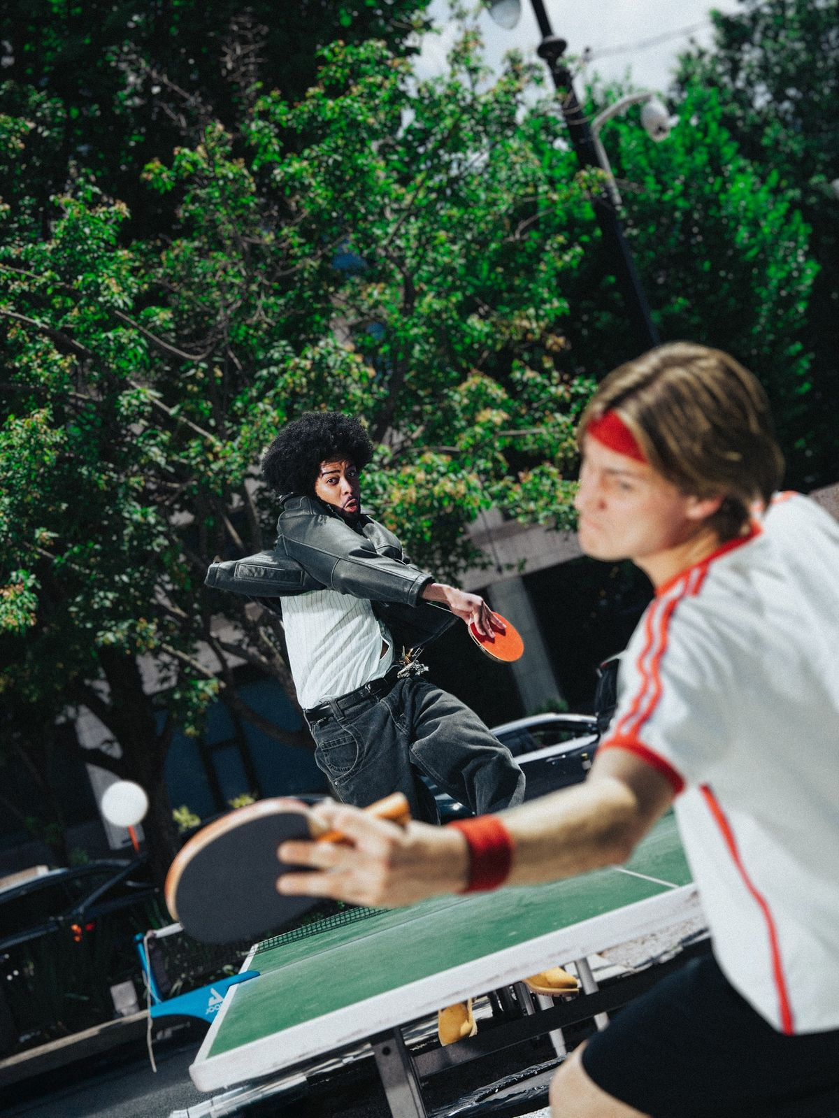 Two players in an outdoor table tennis game